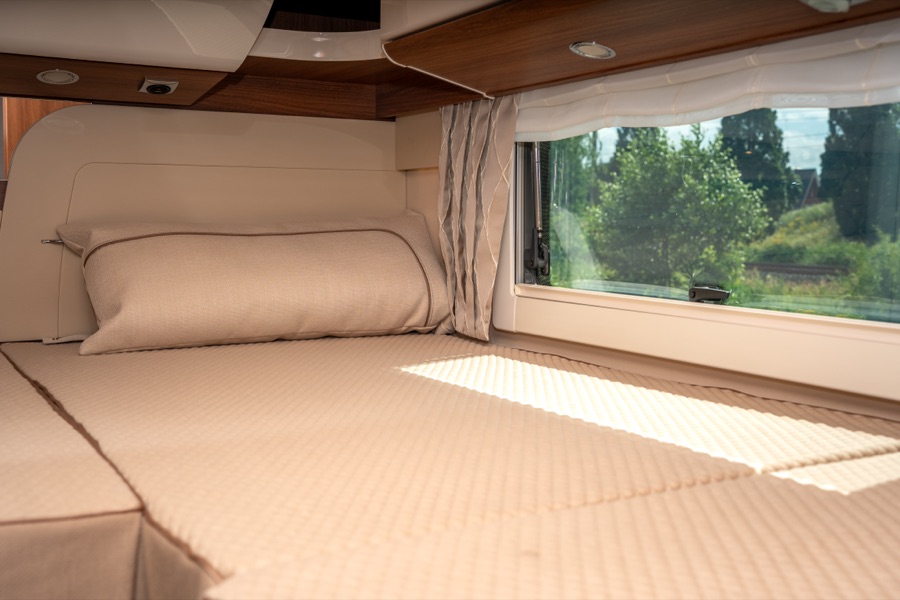 Het opgemaakte bed achterin, met uitzicht door het brede raam